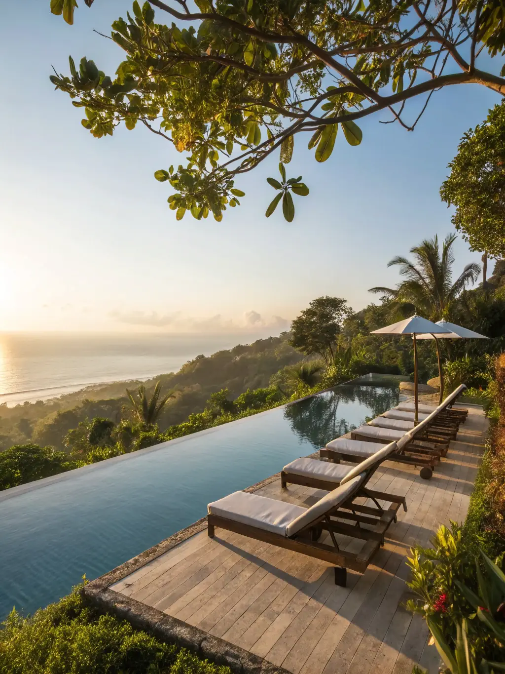 A high-angle, sun-drenched photograph of a private infinity pool overlooking the turquoise Caribbean Sea, with comfortable lounge chairs and a shaded cabana nearby, showcasing the luxury and relaxation offered at the villa.